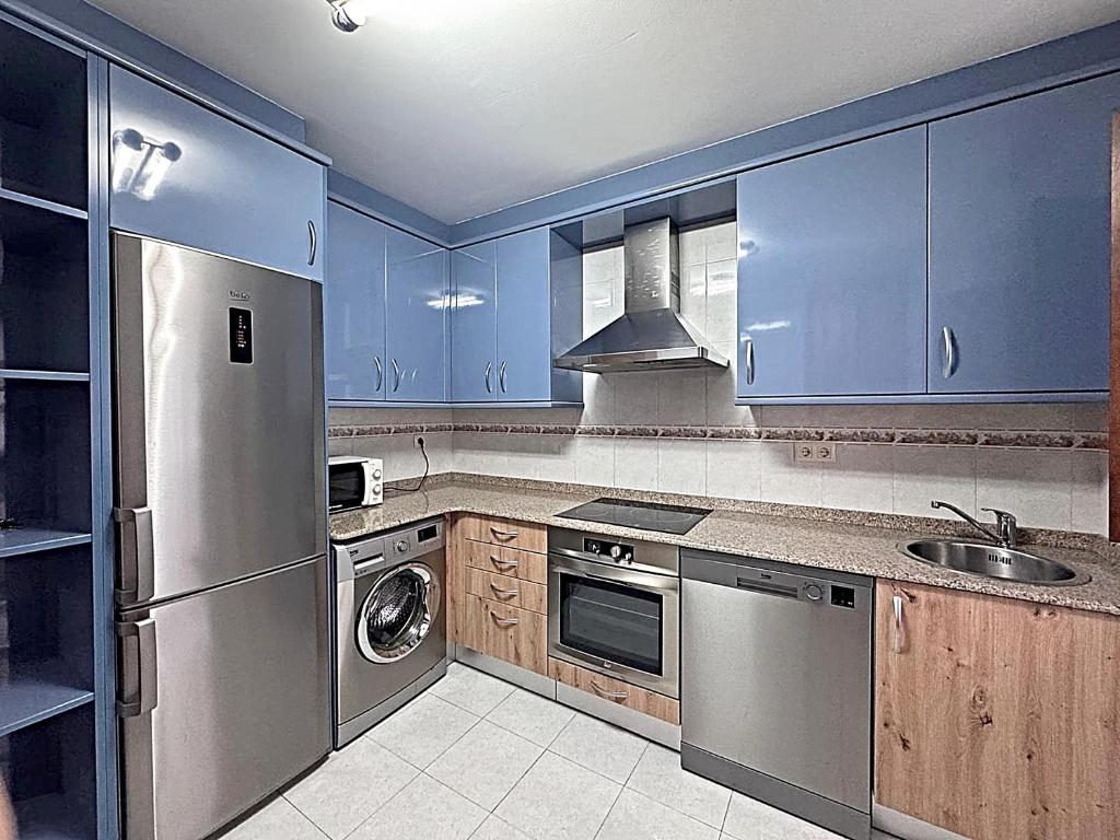 a kitchen with blue cabinets and a stainless steel refrigerator at apartamentos lleguera 1 in Llanes