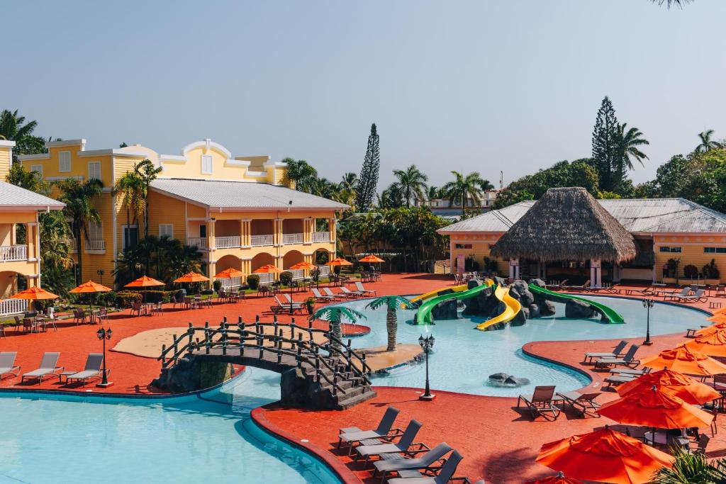 a resort with a large pool with slides and chairs at Telamar Resort in Tela