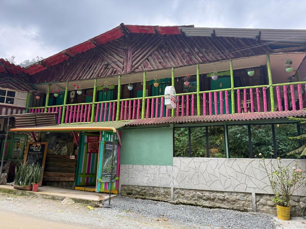 a building with a balcony with pink and green at Cabañas el Portal in Santa Rosa de Cabal