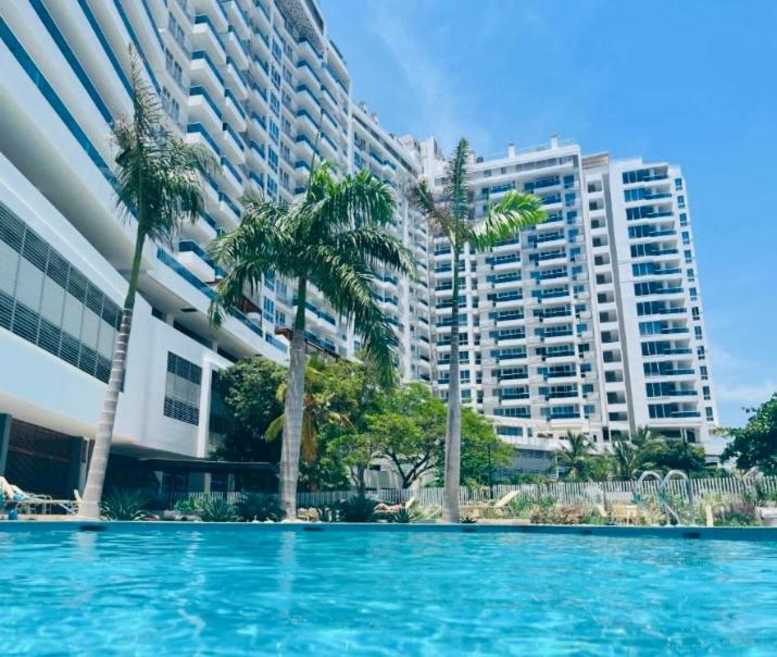 a swimming pool with palm trees in front of a building at Reserva del Mar 539 in Santa Marta