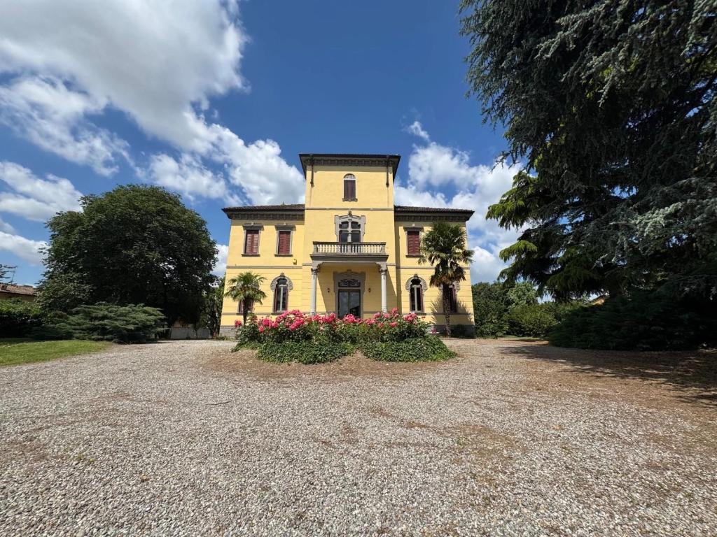 a large yellow house with flowers in the driveway at Villa Cervi in Ronco Todeschino