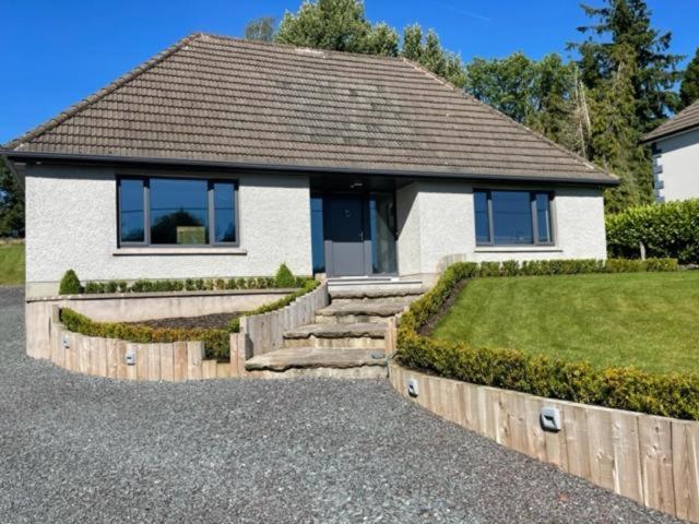 a small white house with a porch and a yard at 5 Bedroom Home Monaghan Town in Monaghan