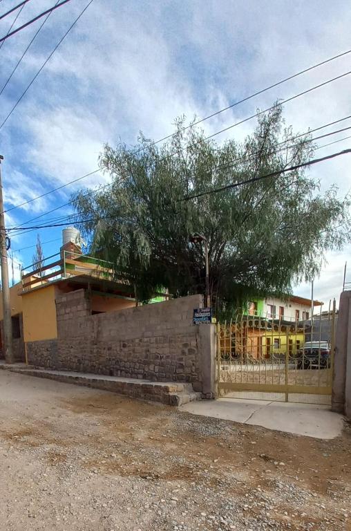 a brick wall with a tree in front of a fence at El Shaddai in Tilcara