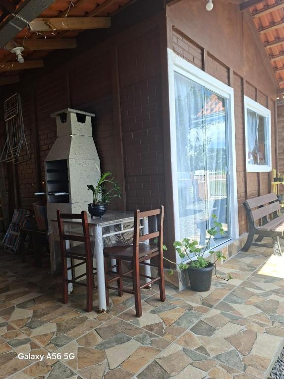 a patio with a table and two chairs and a window at Pousada do vô Bi 02 in São Francisco do Sul