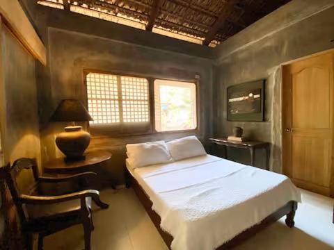a bedroom with a bed and a chair and a window at Caba La Union Gulfside Cottage C2 in Caba