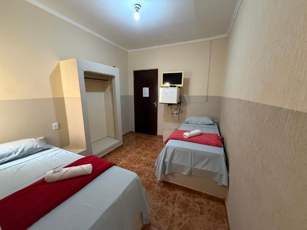 a hotel room with two beds and a tv at Ferrari's Hotell in Miguelópolis