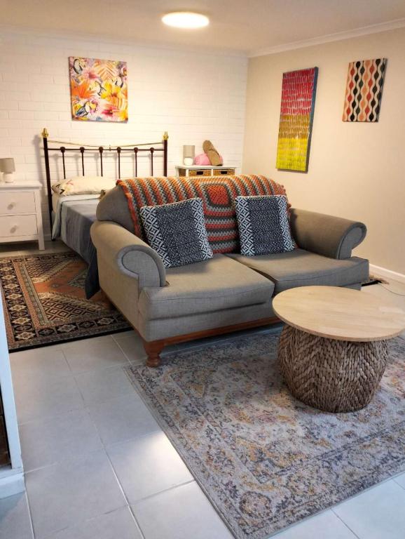 a living room with a couch and a table and a bed at Guest suite-2 beds,private entry, bathroom & laundry in Wollongong