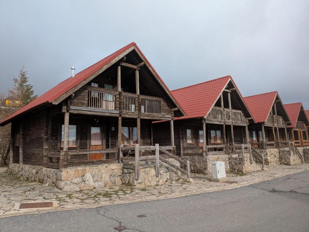 a large wooden building with a red roof at Chalé 24 in Penhas da Saúde