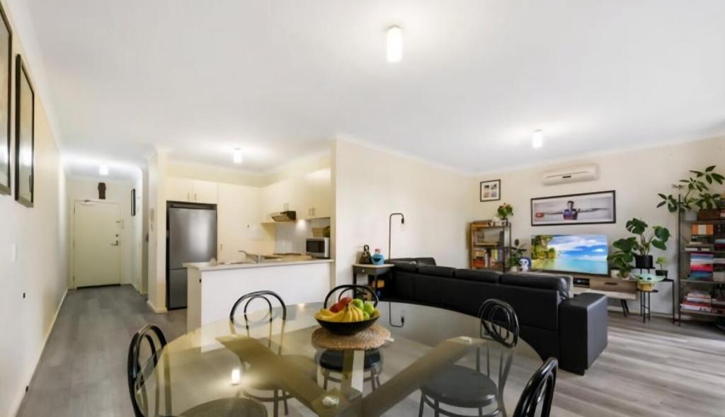 a living room with a table and a black couch at Ground level unit with private courtyard in Melton