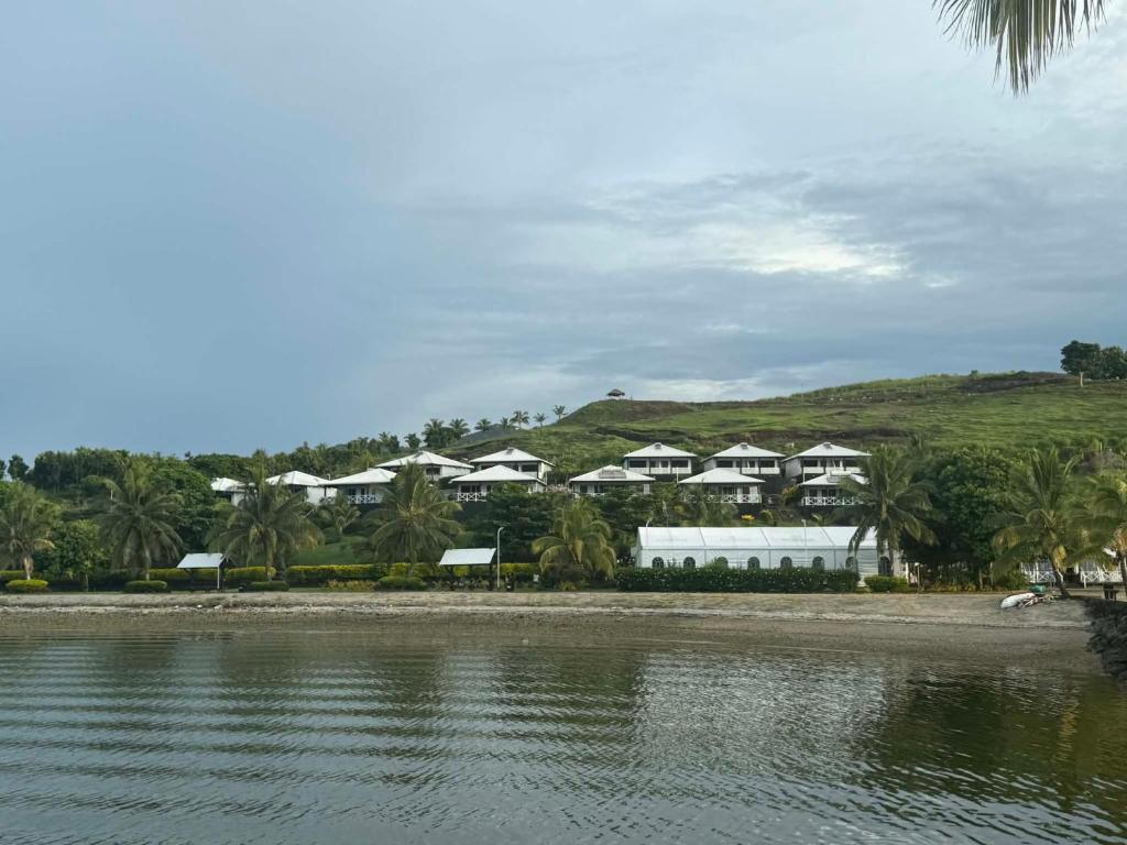 a row of houses on a hill next to a body of water at Dua Dua Beach Resort in Rakiraki