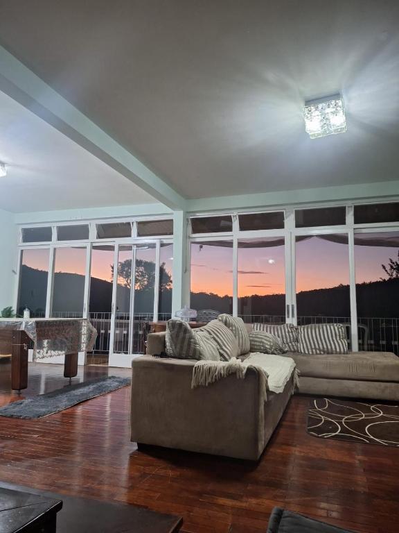a living room with a couch in front of windows at Pousada Essenza lindoía in Águas de Lindoia