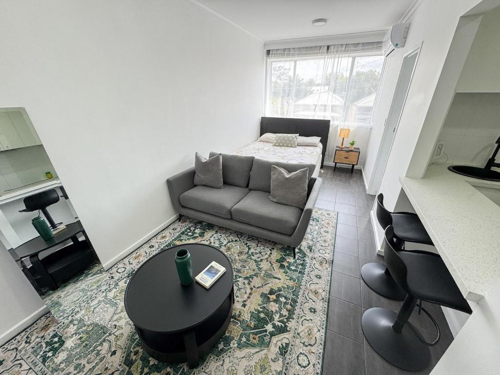 a living room with a couch and a table at Clean Bright Studio Apartment - Walkable Location in Melbourne