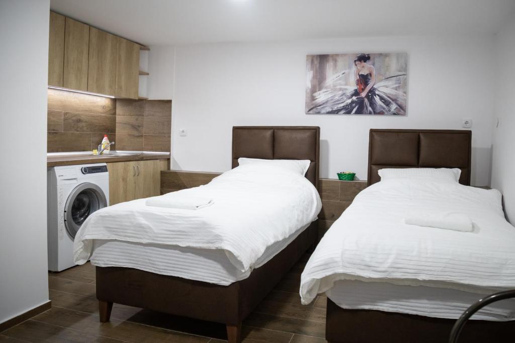 two beds in a kitchen with a washing machine at Apartman centar 18 in Ub