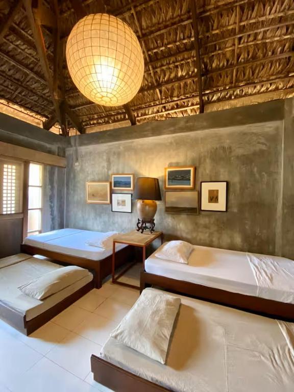 a bedroom with three beds and a chandelier at Caba La Union Gulfside Cottage C3 in Caba