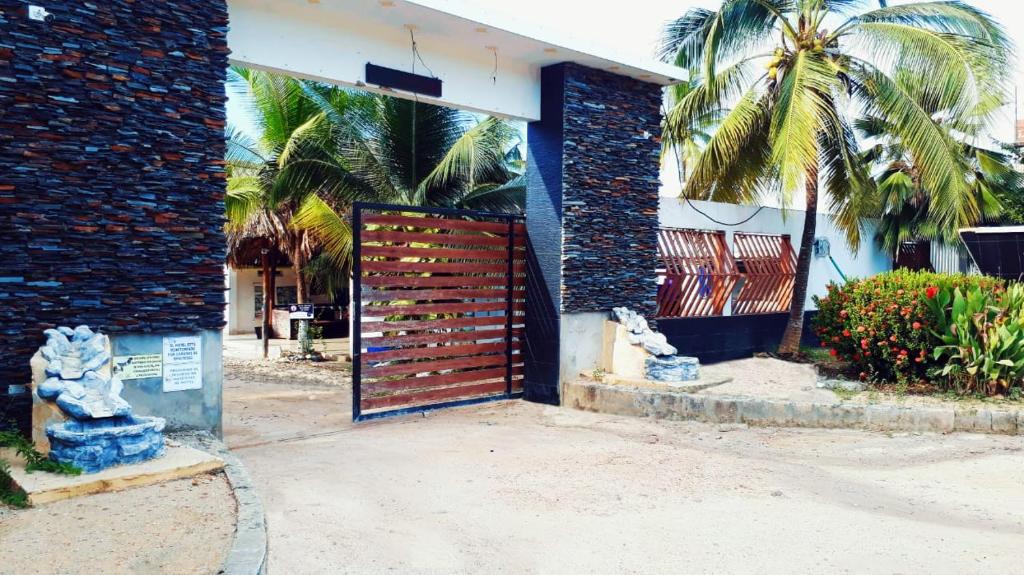 a wooden gate to a building with palm trees at Alojamiento PLAYA DORADA Coveñas in Coveñas