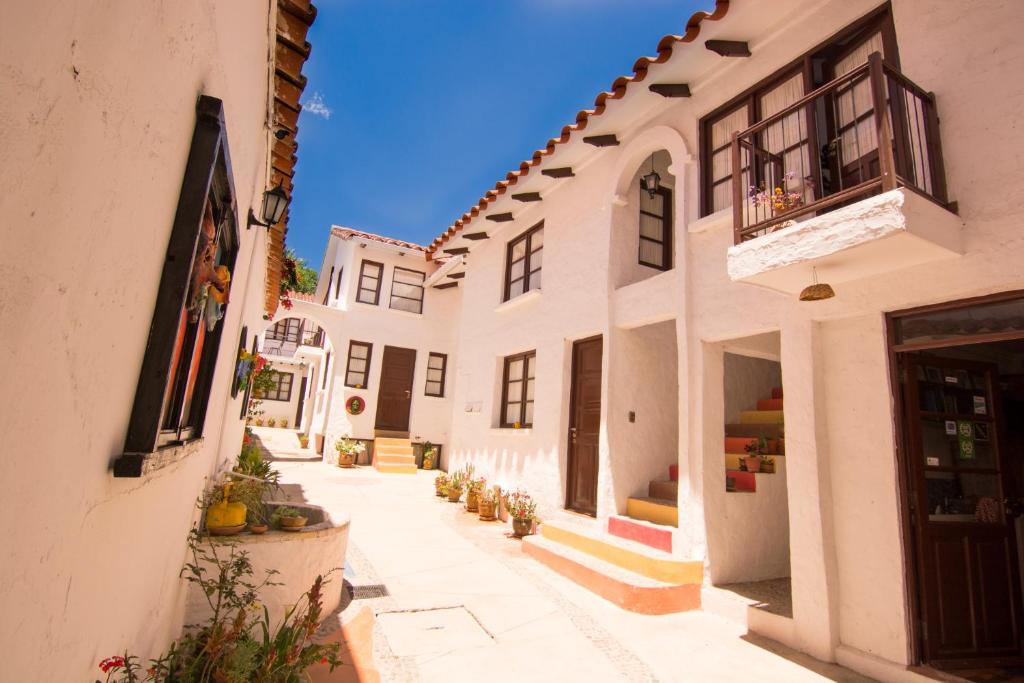 un callejón con edificios blancos y plantas en la acera en CasArte Takubamba B&B, en Sucre