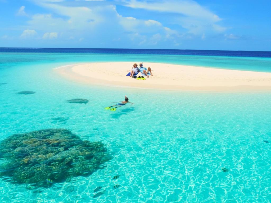 a group of people sitting on a beach in the ocean at Bougain Villa Gemanafushi in Gemanafushi