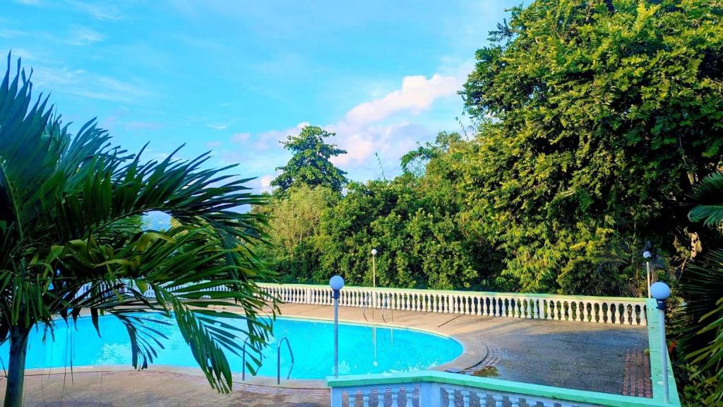 a swimming pool with a white fence and trees at Harmony Place at Hillside in Puerto Princesa City