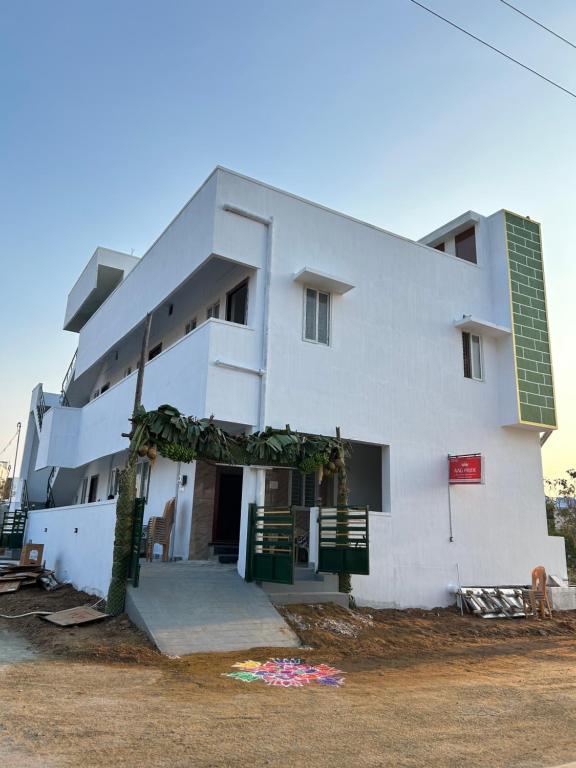 a white building with green shutters on it at AAG Pride serviced apartments in Pollāchi