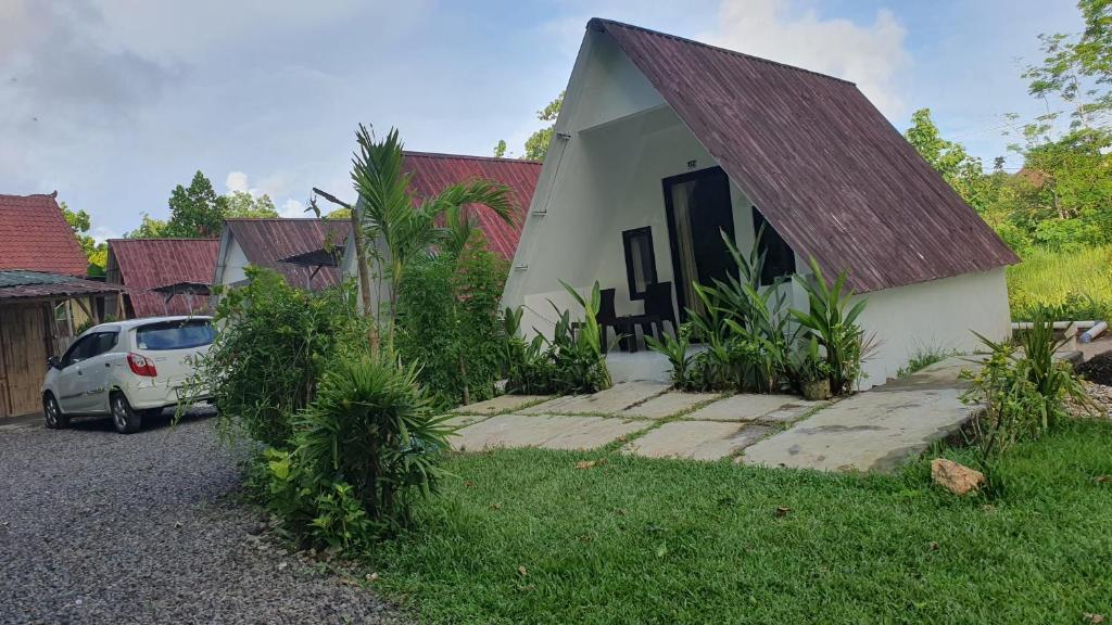 a house with a car parked in front of it at the bamboo Bali Cabin in Nusa Dua