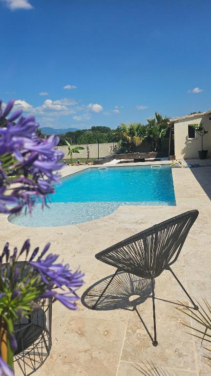 a table and a chair next to a swimming pool at Mas des Palmiers in Grignan