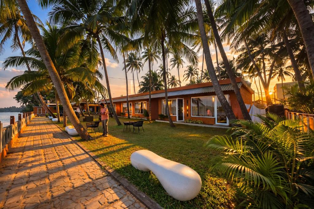 a person standing in front of a house with palm trees at TAM BoSa Beach Retreat in Kalyānpur