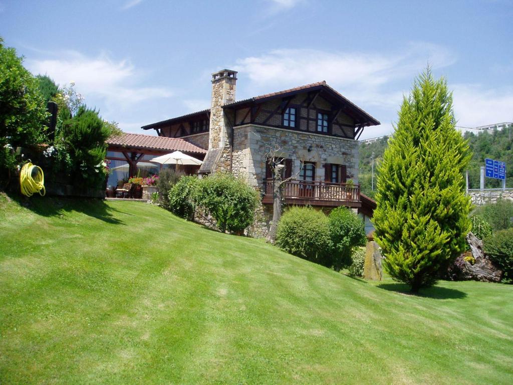 una casa grande en una colina con un patio verde en Casa Rural Erdikoetxe, en Galdakao