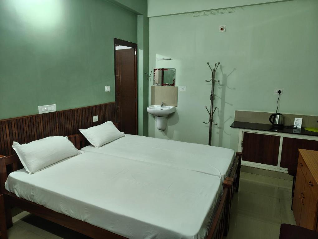 a bedroom with a large bed and a sink at Staysafe in Kattakkada