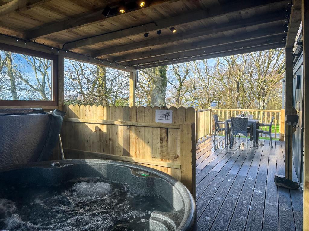 a hot tub on a wooden deck with a table at Herdwick Lodge - Uk51383 in Westward
