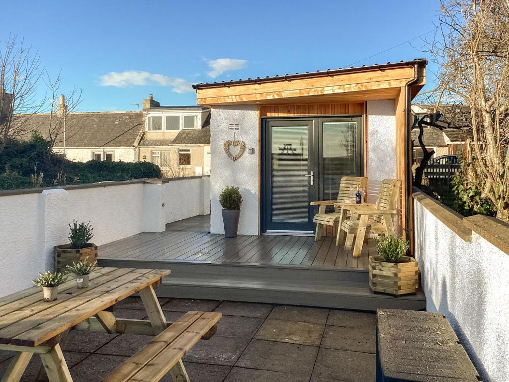 a wooden deck with a table and benches on a balcony at Wee Shore Walk in Balintore