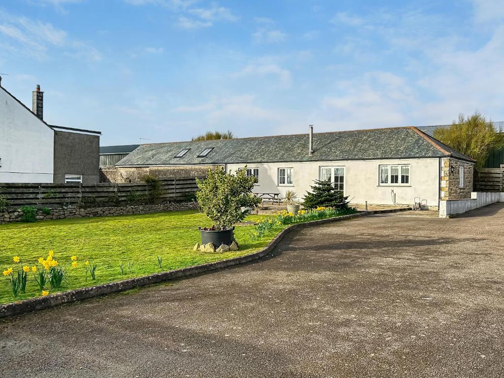 a white house with a tree in a yard at The Barn in Helston