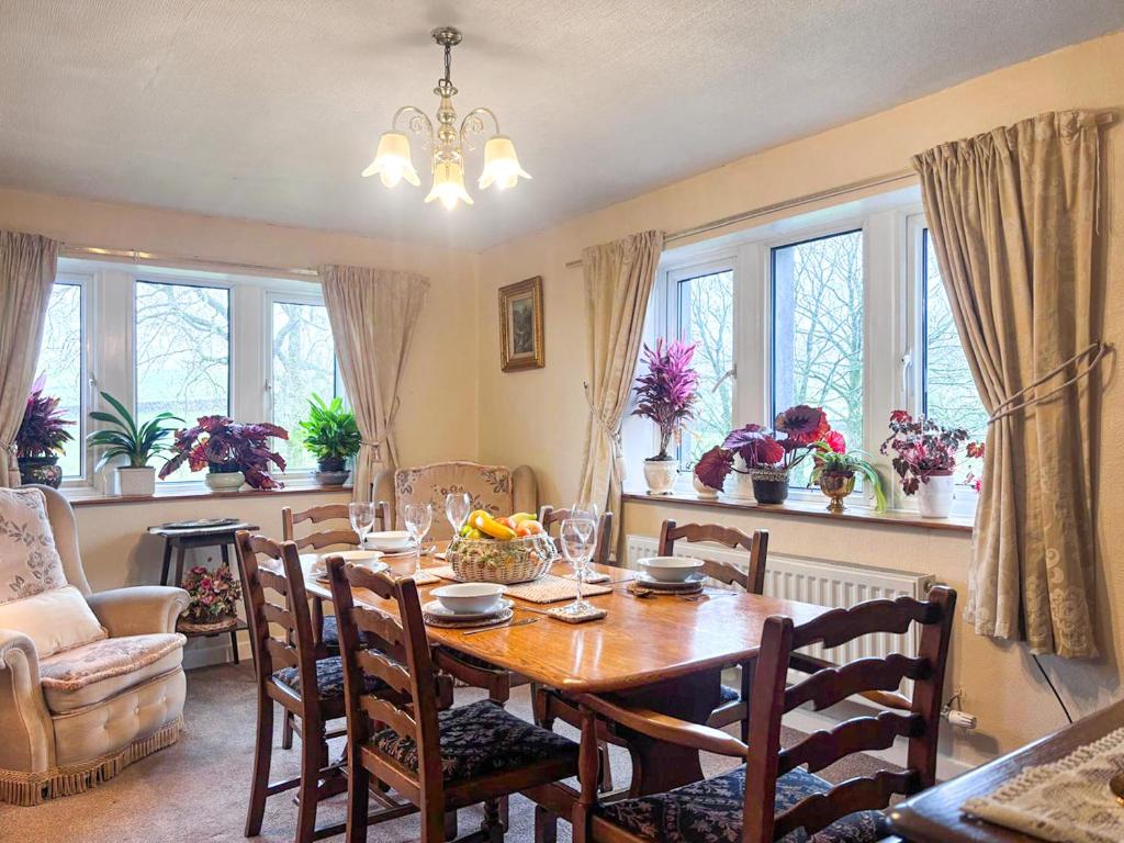 a dining room with a table and chairs and windows at Blindbeck Holiday Cottage in Settle
