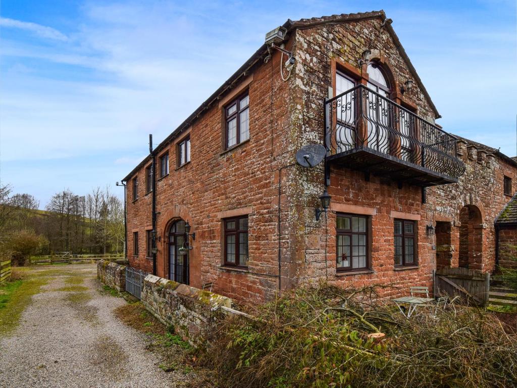 an old brick building with a balcony on it at The Barley Mow in Kirkoswald