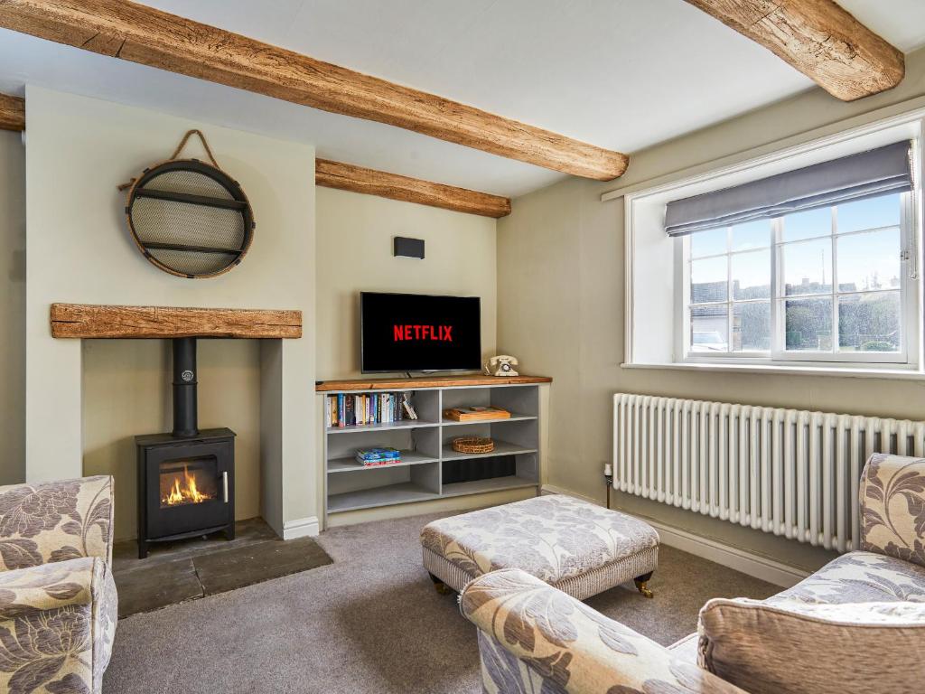 a living room with a fireplace and a tv at Hayy Bondgate Cottage in Harewood