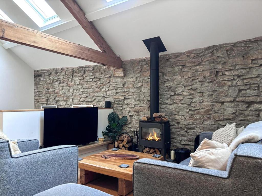 a living room with a stone wall with a fireplace at Pletts Barn in Grassington