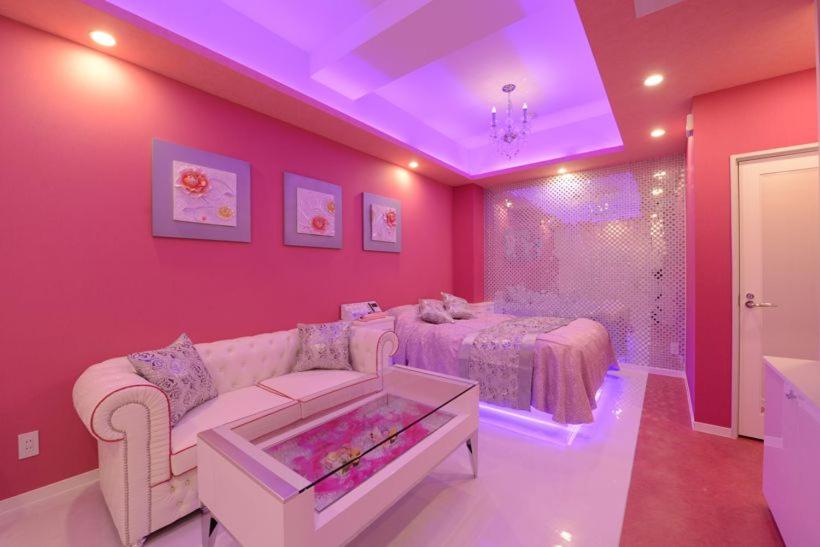 a pink room with a couch and a bed at NUDA Toyama in Takaoka