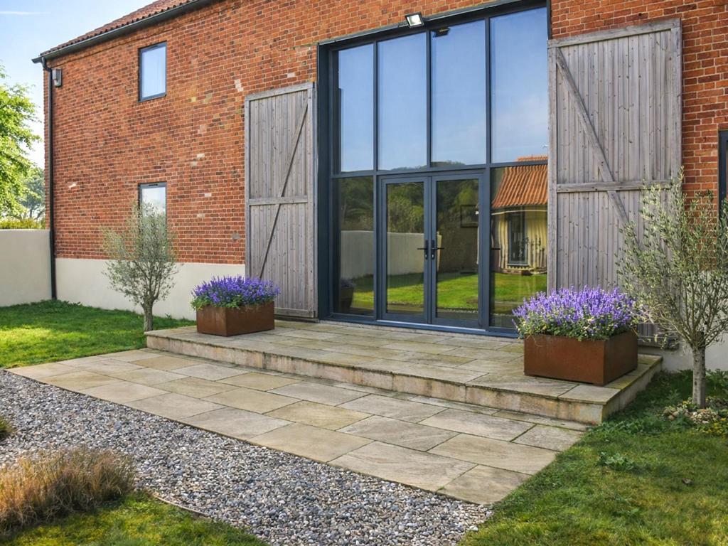 a glass extension to a house with purple flowers at South Barn in Heydon