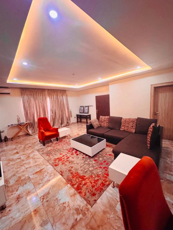 a living room with a couch and a red chair at Liberty Suite - Abuja in Abuja