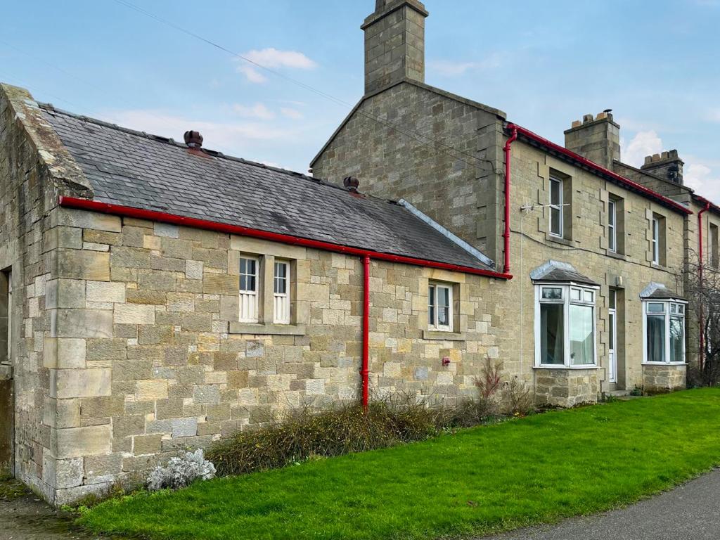 an old stone building with a roof and grass at Paddock Cottage in Morpeth