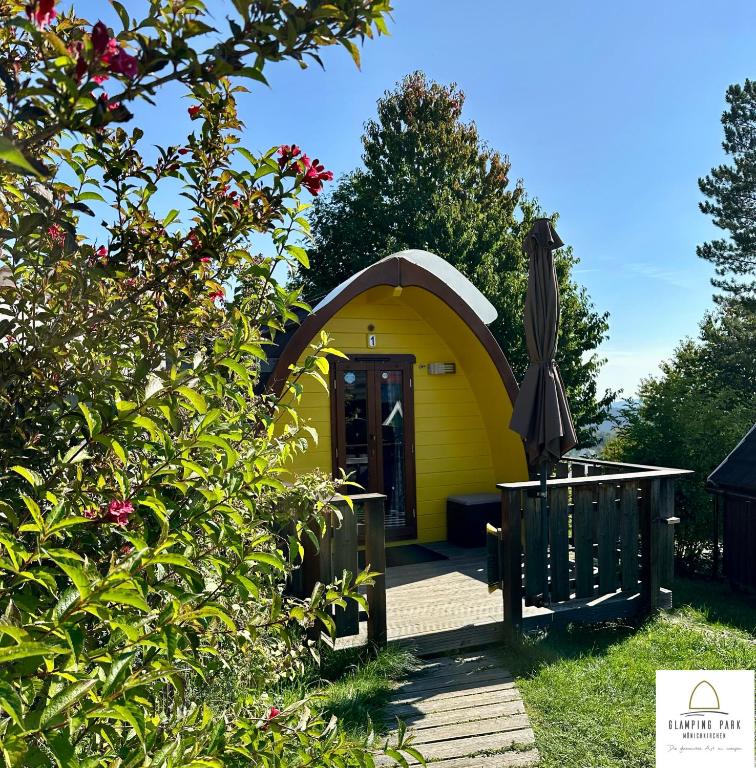 a small yellow house with a porch and an umbrella at Glamping Park in Mönichkirchen