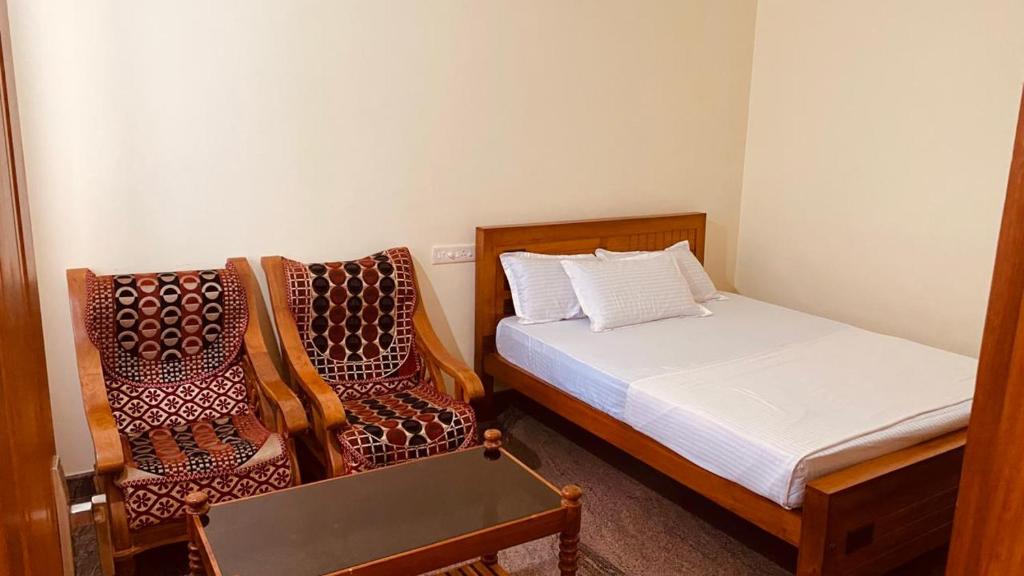 a small bedroom with a bed and two chairs at Celestial Homestay in Wayanad