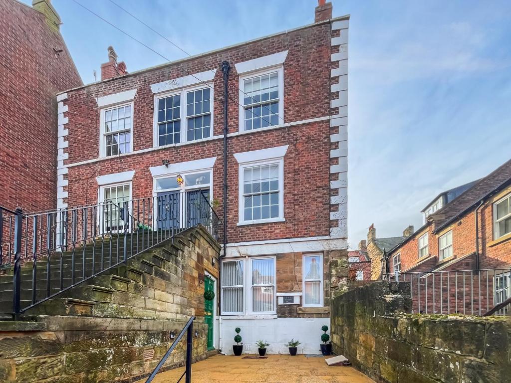 a brick house with a staircase in front of it at Old Steamship Quarters in Whitby