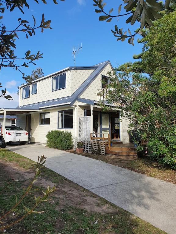 a white house with a car parked in the driveway at Estuary Hideaway in Whangamata
