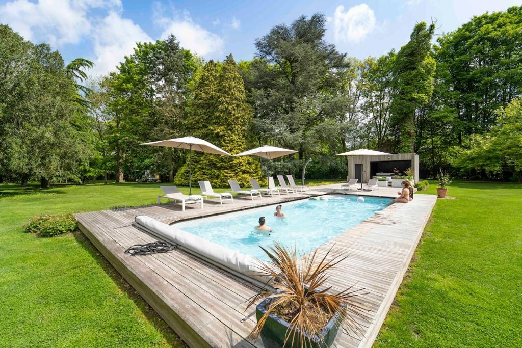 a pool with chairs and umbrellas in a yard at La Château de Toile, Gîte du Marronnier in Hersin-Coupigny