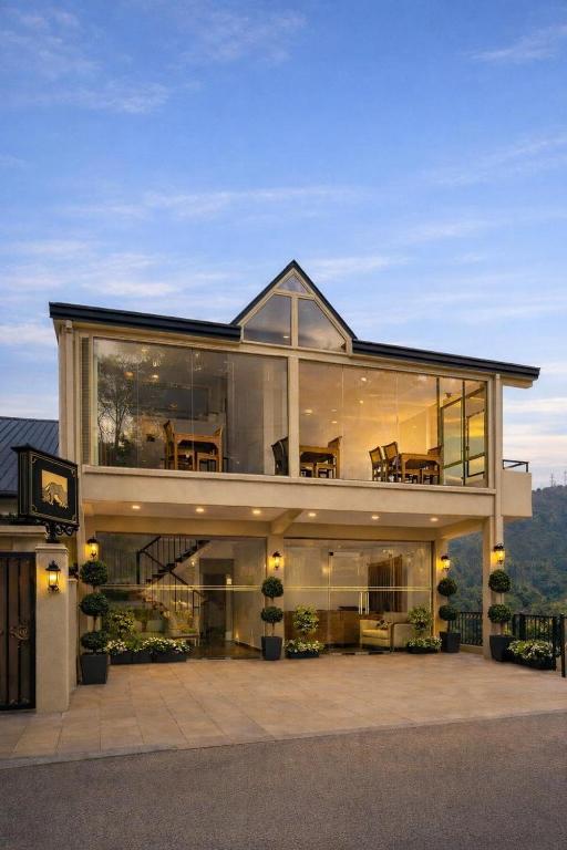 a large house with a lot of glass at La Cottage in Nuwara Eliya