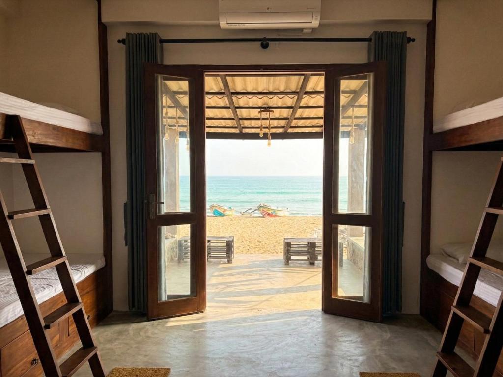 a room with a door open to the beach at Trinco Beach Bunks in Trincomalee
