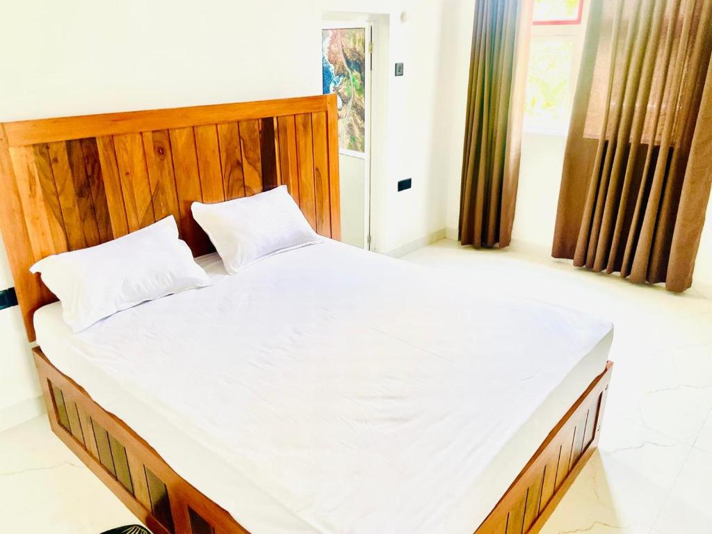 a bedroom with a large bed with a wooden headboard at Green Crown Villa in Polonnaruwa
