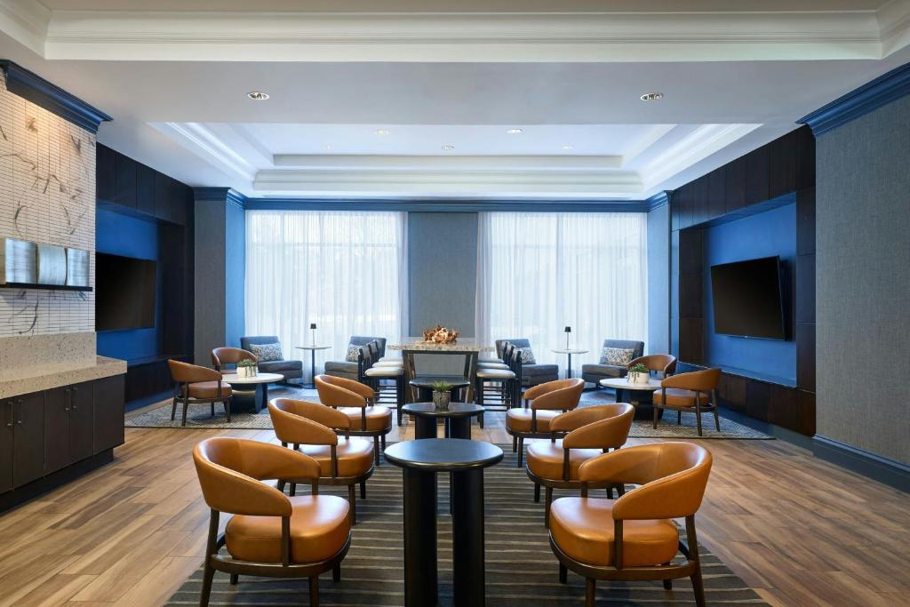 a waiting room with tables and chairs and a tv at Bridgewater Marriott in Bridgewater