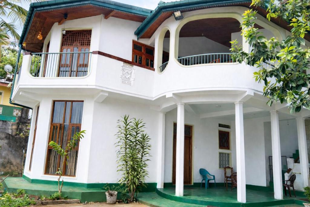 a white house with a balcony at V6 Nest in Hali Ela