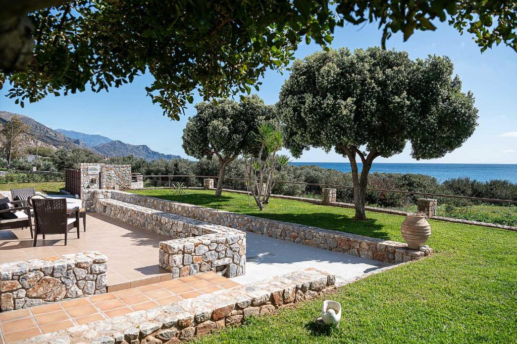 a garden with a stone wall and a table and chairs at Casa Horizon in Palaiochora